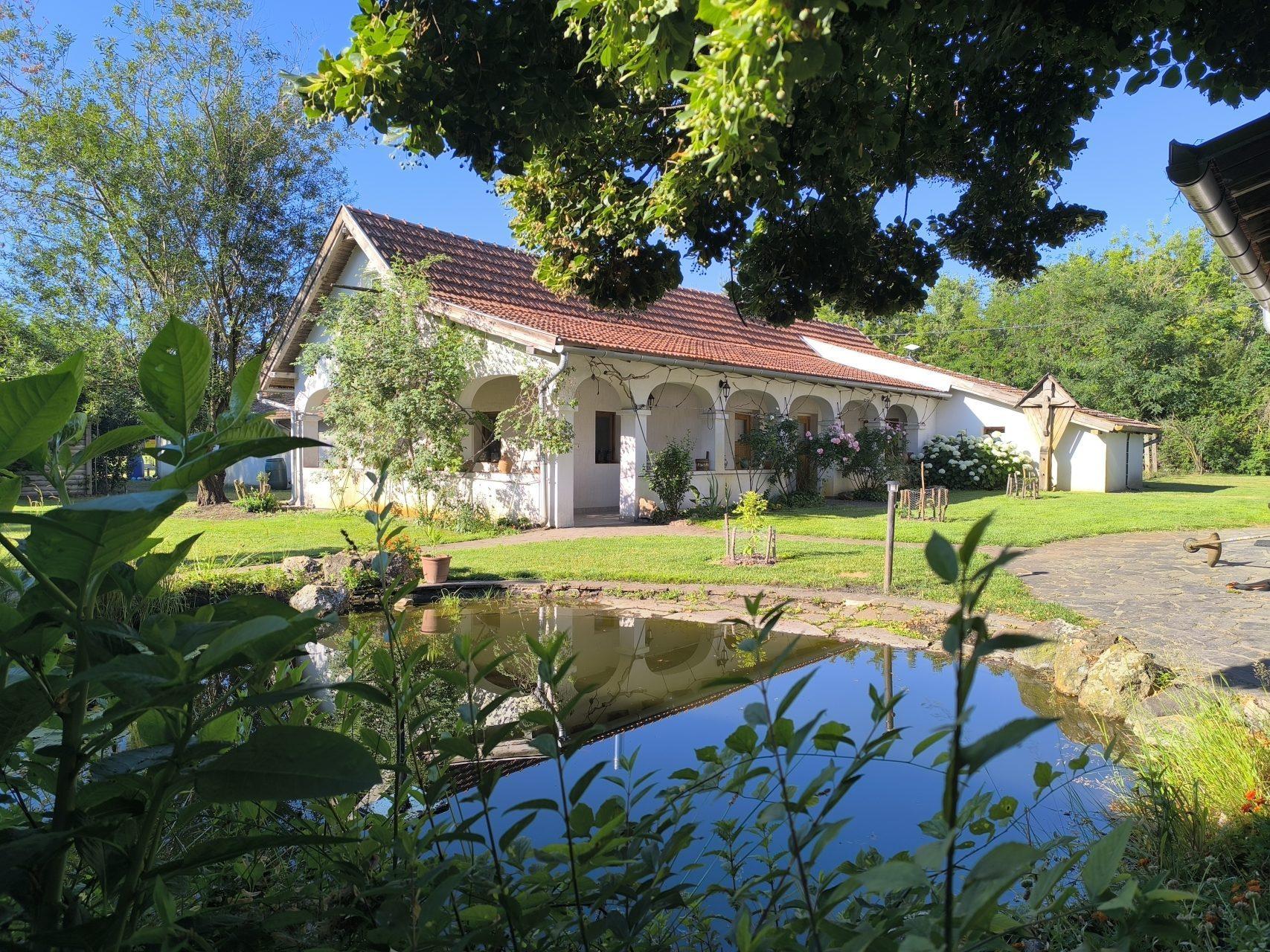 The main house with its charming arched colonnade, reflected in the garden pond